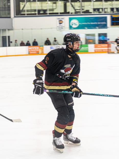 Hockey player in black jersey skating with stick